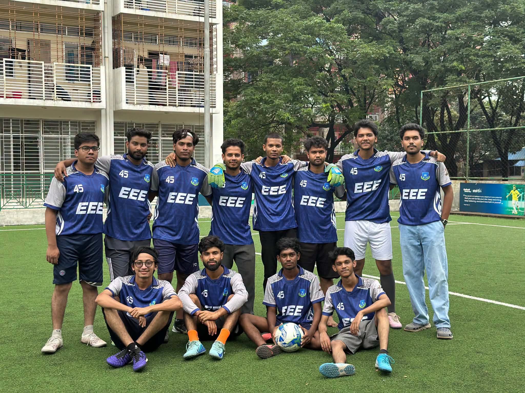EEE football team standing together in matching blue jerseys on a campus pitch